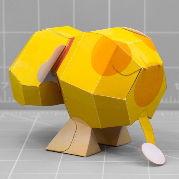 A photo of a papercraft depicting Oatchi, a yellow space dog with 2 legs and no nose from the upcoming Pikmin 4 game. The photo is taken from the back