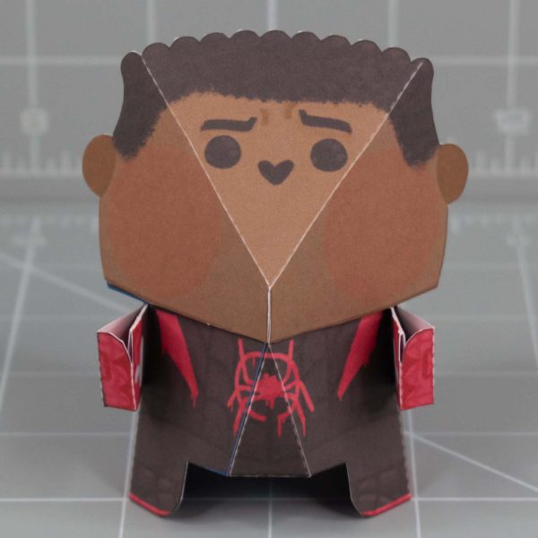 A photo of a Fold Up Friend papertoy of Miles Morales Spider-Man. He has a large round head with a small cute face.