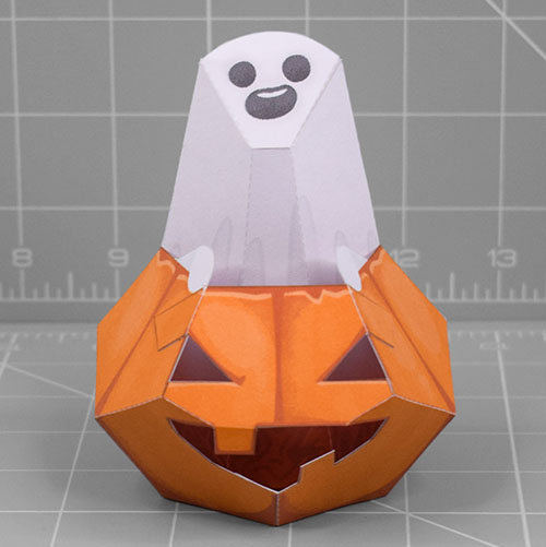A papercraft of a ghost sitting inside of a Halloween pumpkin